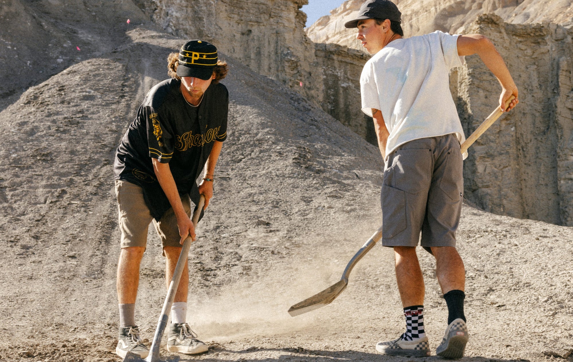 Two models wearing the 686 Unwork shorts as they shovel dirt to build a bike track. 