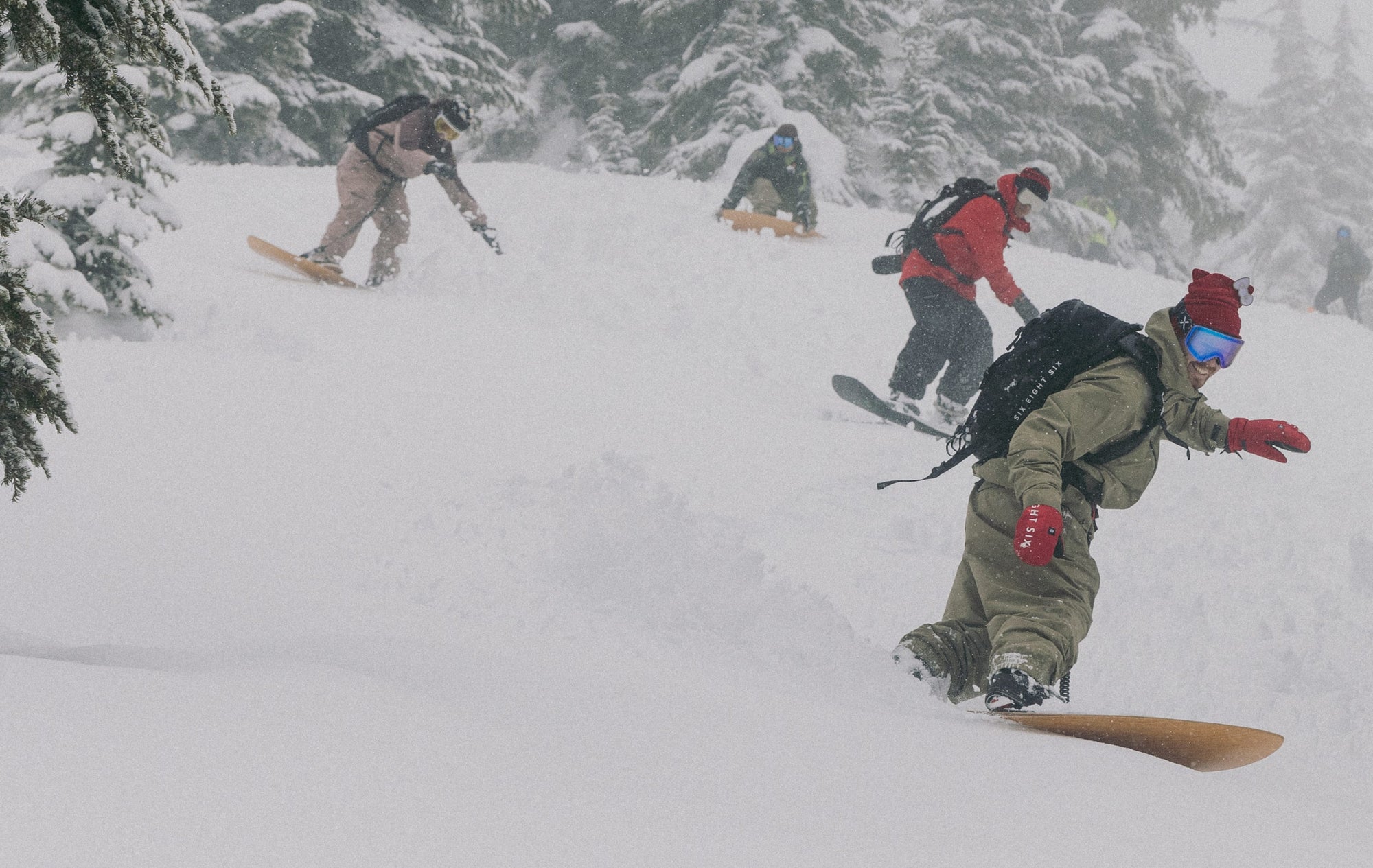 686 team riders snowboarding down a snowy mountain wearing an assortment of 686 gear.
