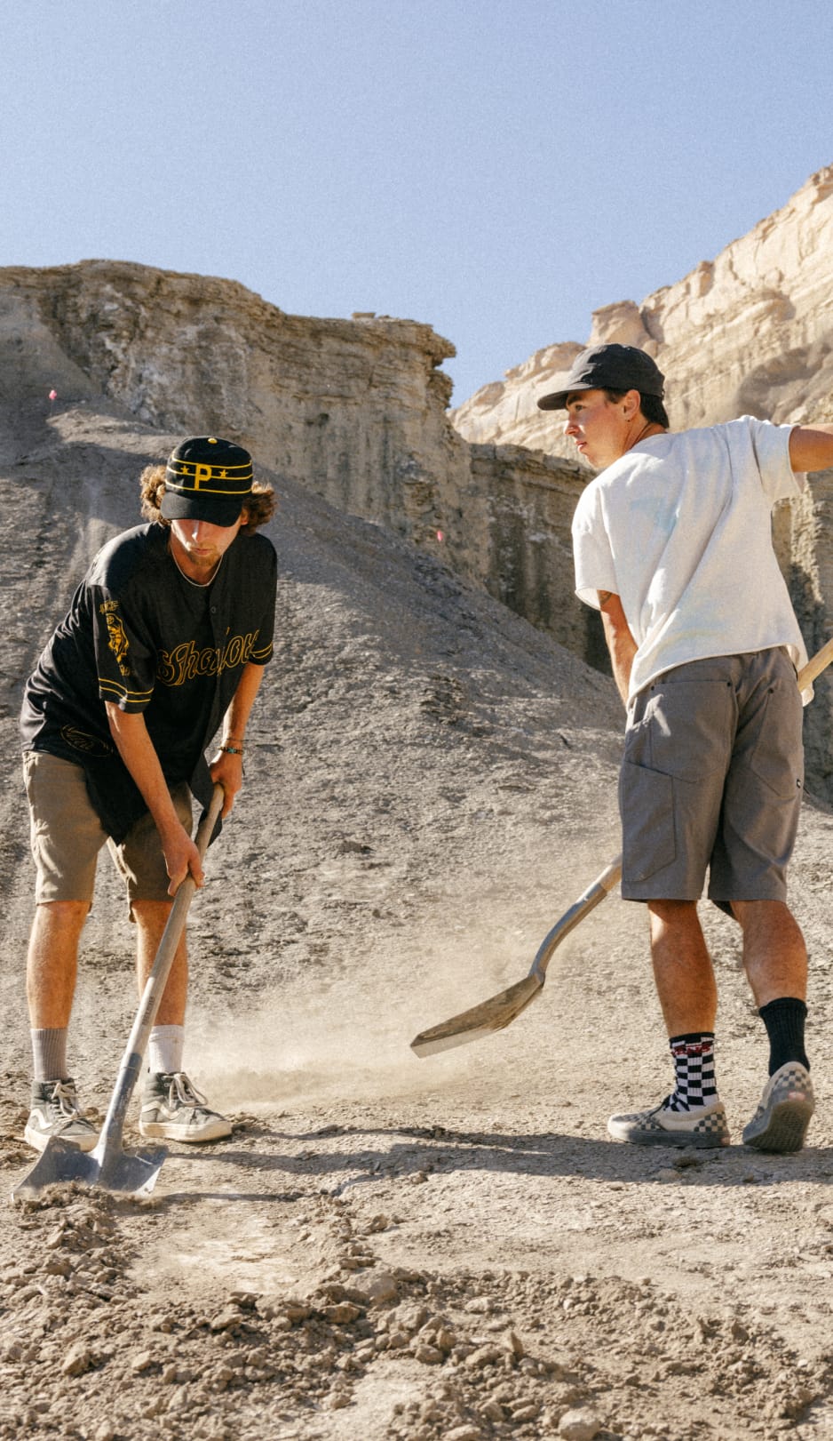 Two models wearing the 686 Unwork shorts as they shovel dirt to build a bike track. 